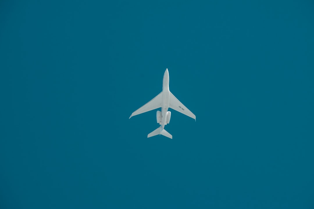 a white jet flying through a blue sky