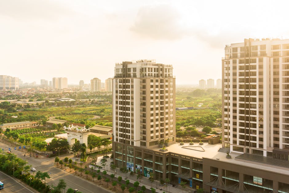 Elevated view of urban landscape with skyscrapers and green fields under sunlight.