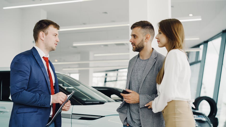 Car salesman assisting a couple in a modern showroom with a luxury car.