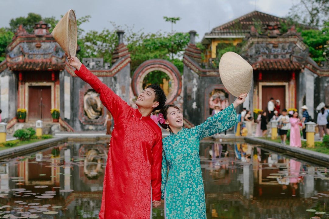 Couple in traditional vietnamese ao dai holding conical hats