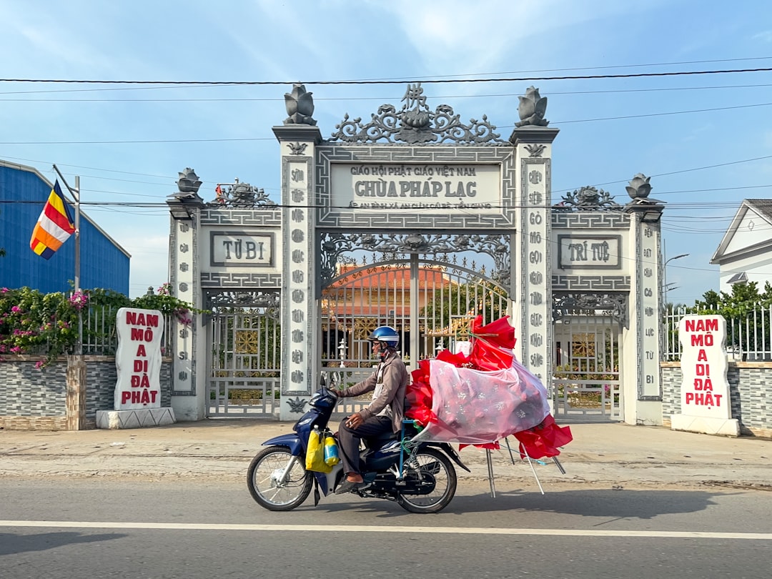 A man riding a motorcycle down a street past a gate