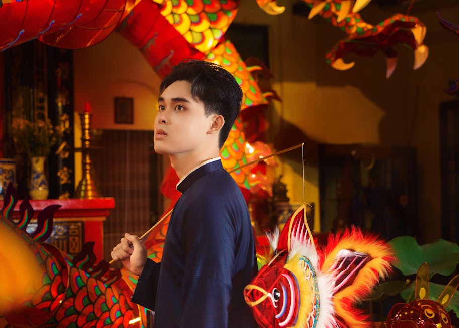 Vietnamese man in traditional costume with vibrant dragon and fish lanterns.