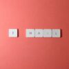 Flat lay of keyboard letter tiles spelling 'email' on coral backdrop.