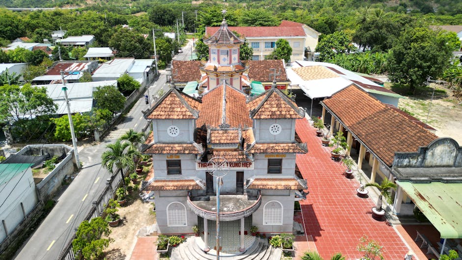 Aerial photo of a historic Vietnamese church surrounded by lush greenery and neighborhood buildings.