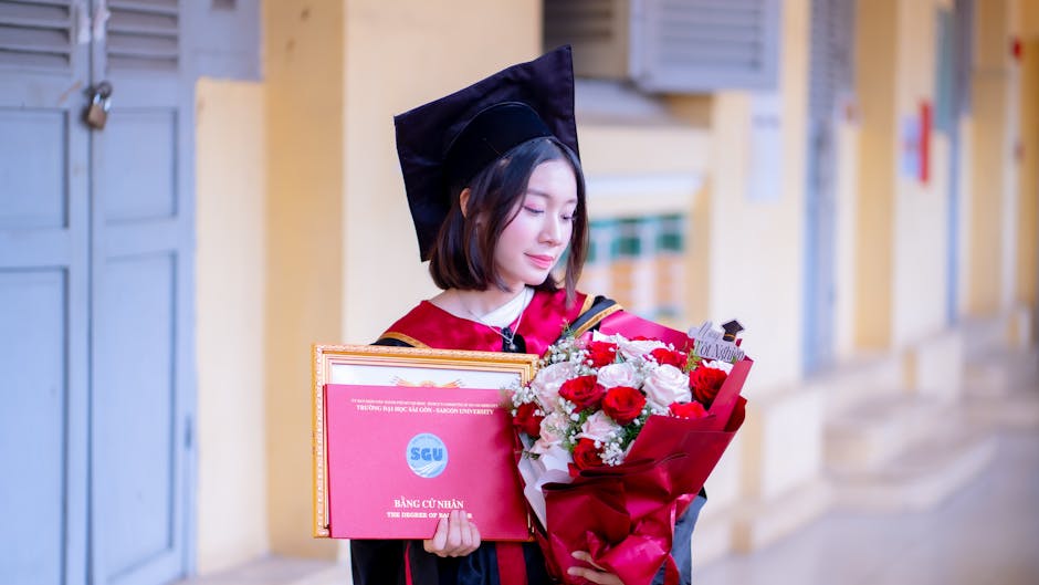 A young woman in a graduation cap and gown holds a certificate and bouquet, symbolizing academic achievement.