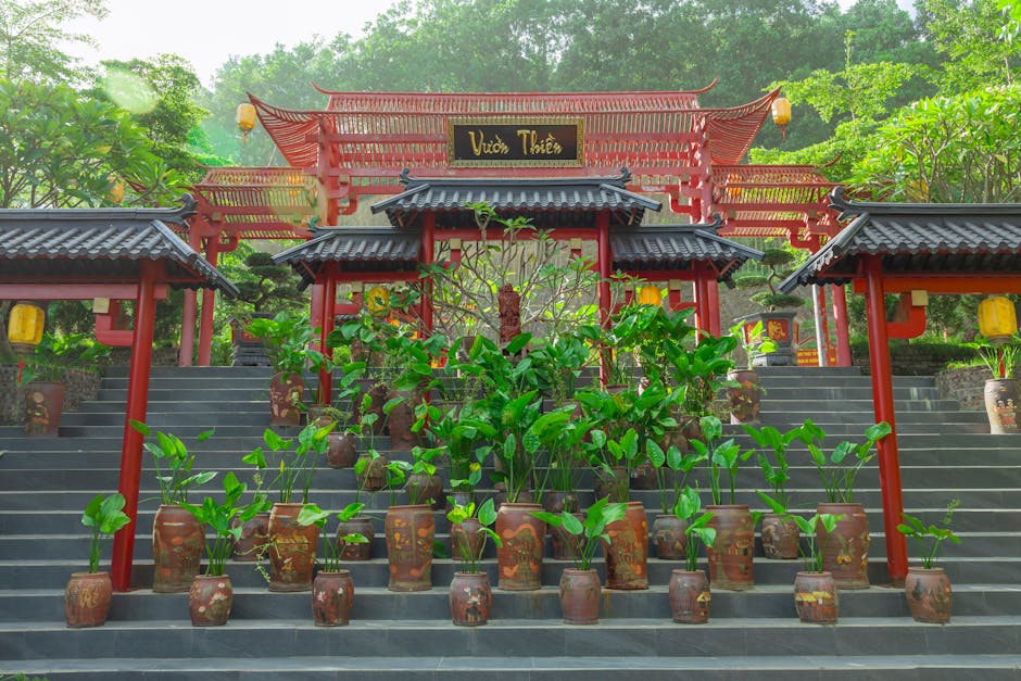 Entrance to a peaceful Asian garden with red wooden architecture and potted plants.