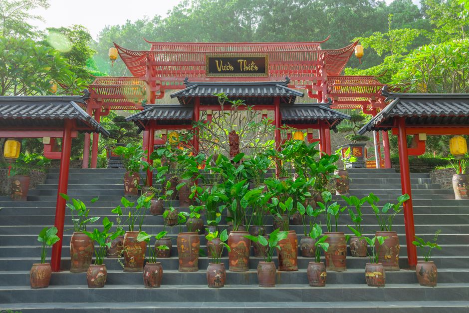 Entrance to a peaceful Asian garden with red wooden architecture and potted plants.