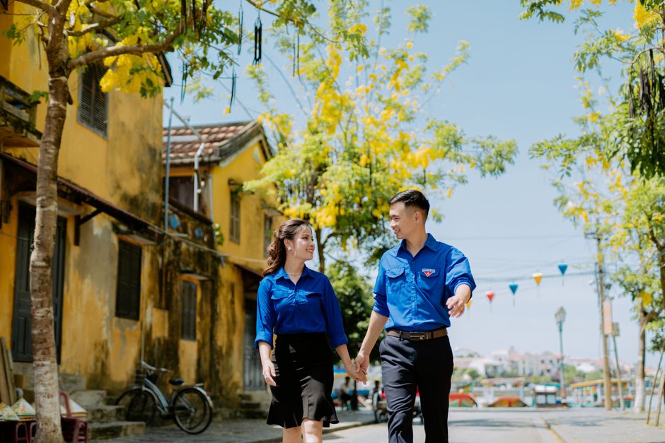 Asian couple walking hand in hand on a sunny street, capturing romance and happiness.