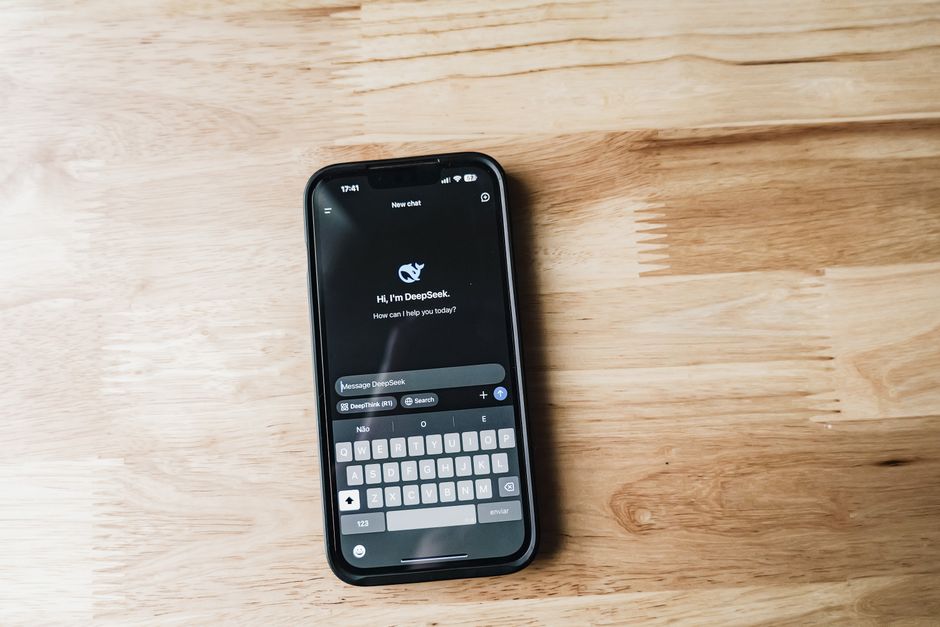 Close-up of a smartphone displaying AI chat interface on a wooden table.