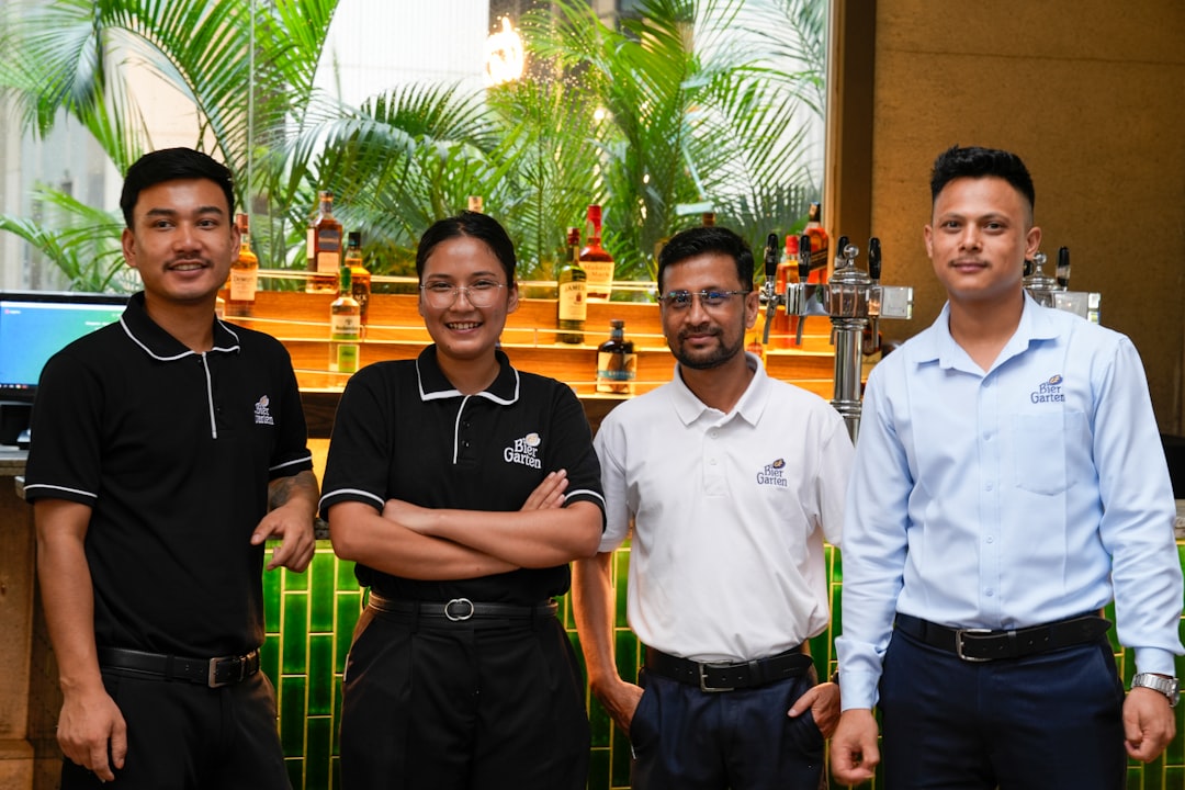 Four smiling staff members pose in front of a bar.