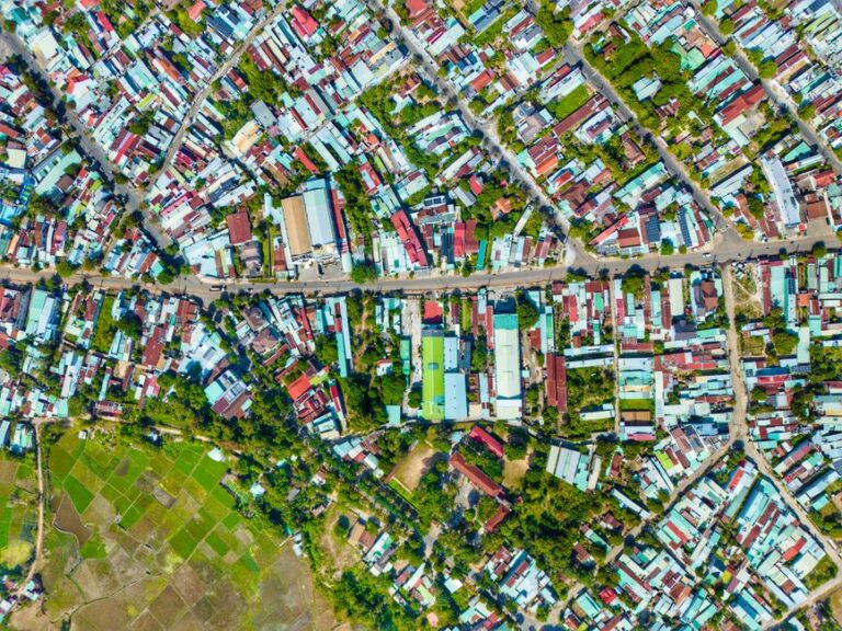 Aerial shot of a colorful urban neighborhood, showcasing tightly packed houses and greenery.