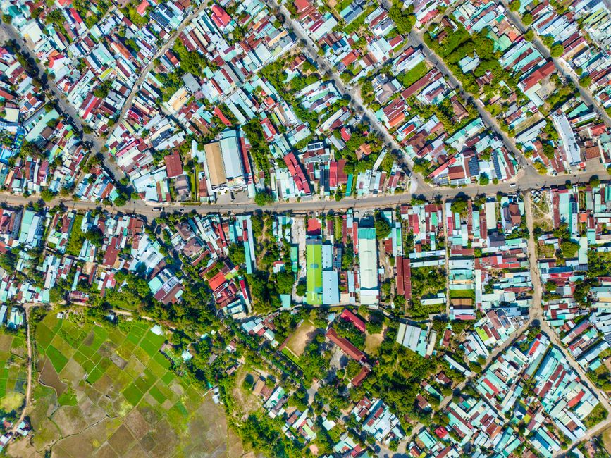 Aerial shot of a colorful urban neighborhood, showcasing tightly packed houses and greenery.