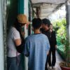 People talking on a narrow outdoor balcony with plants